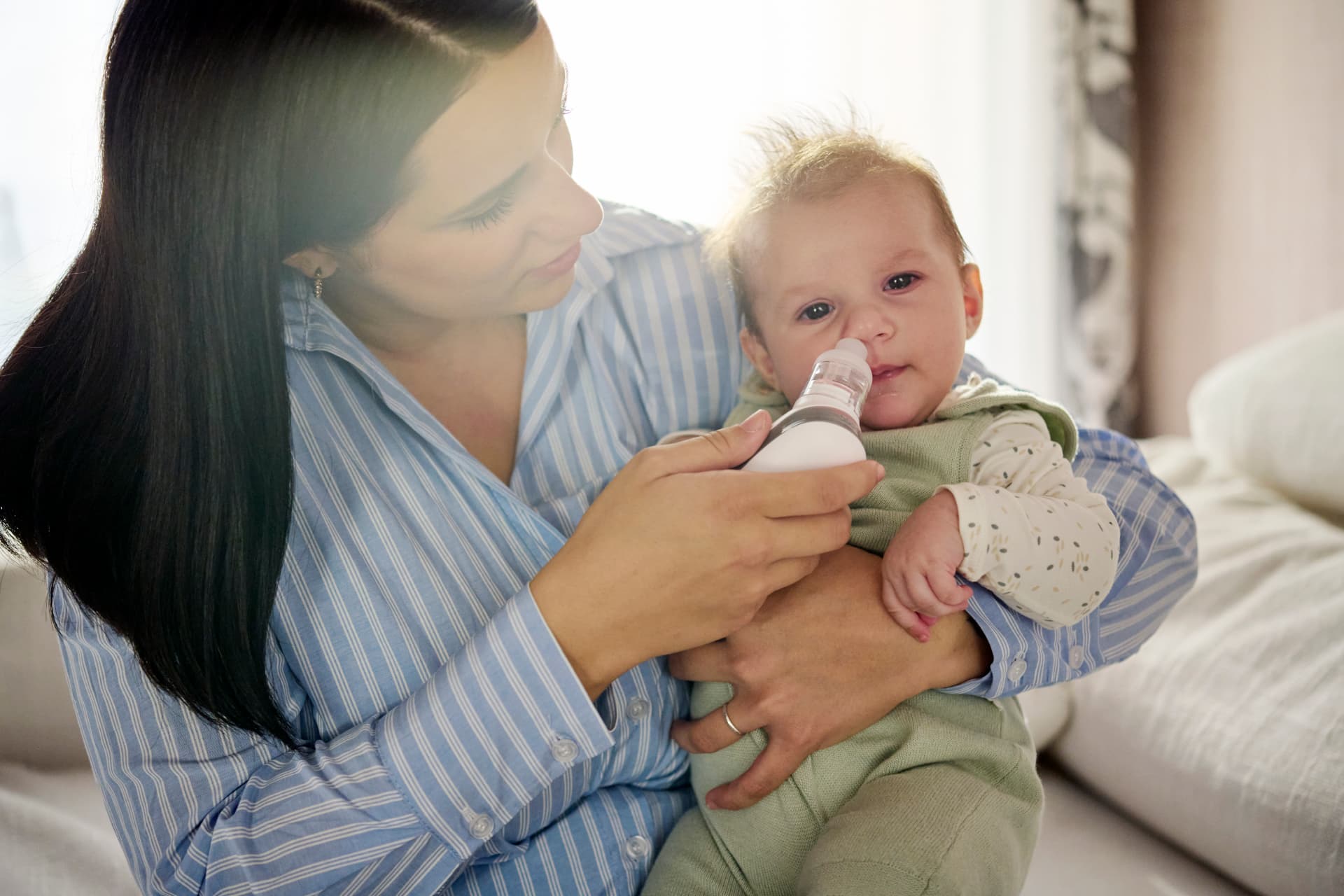 Une mère utilise l’aspirateur nasal électrique Nuvita sur son enfant